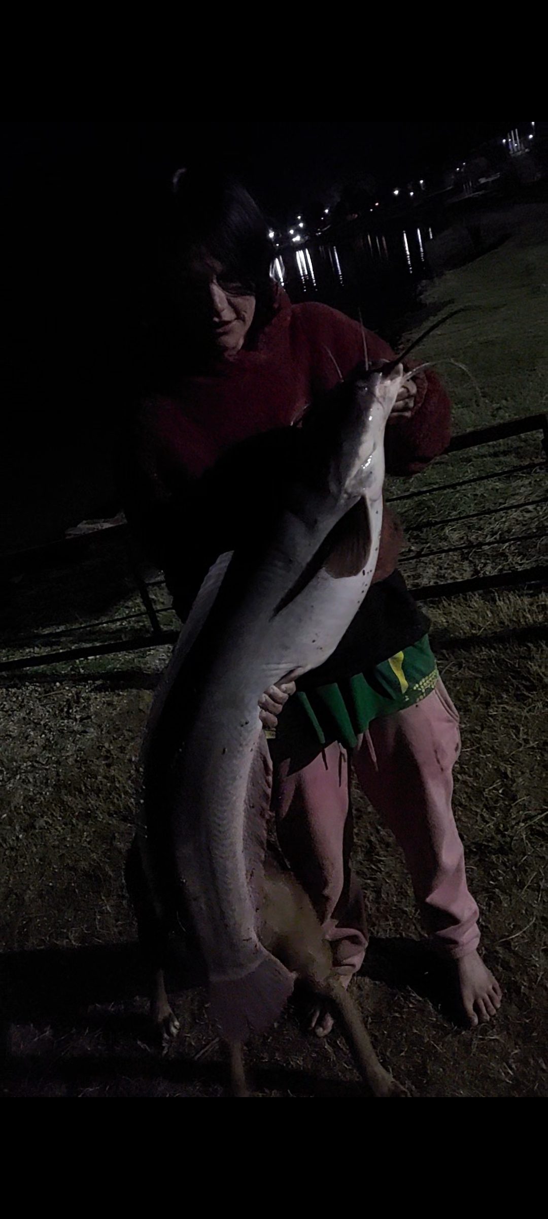 Holding a catfish caught after dark by the water's edge