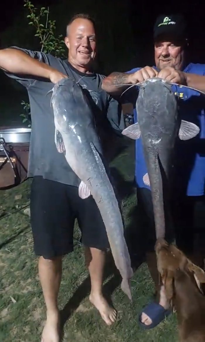 Trevor and Justin holding two big catfish at night by the river